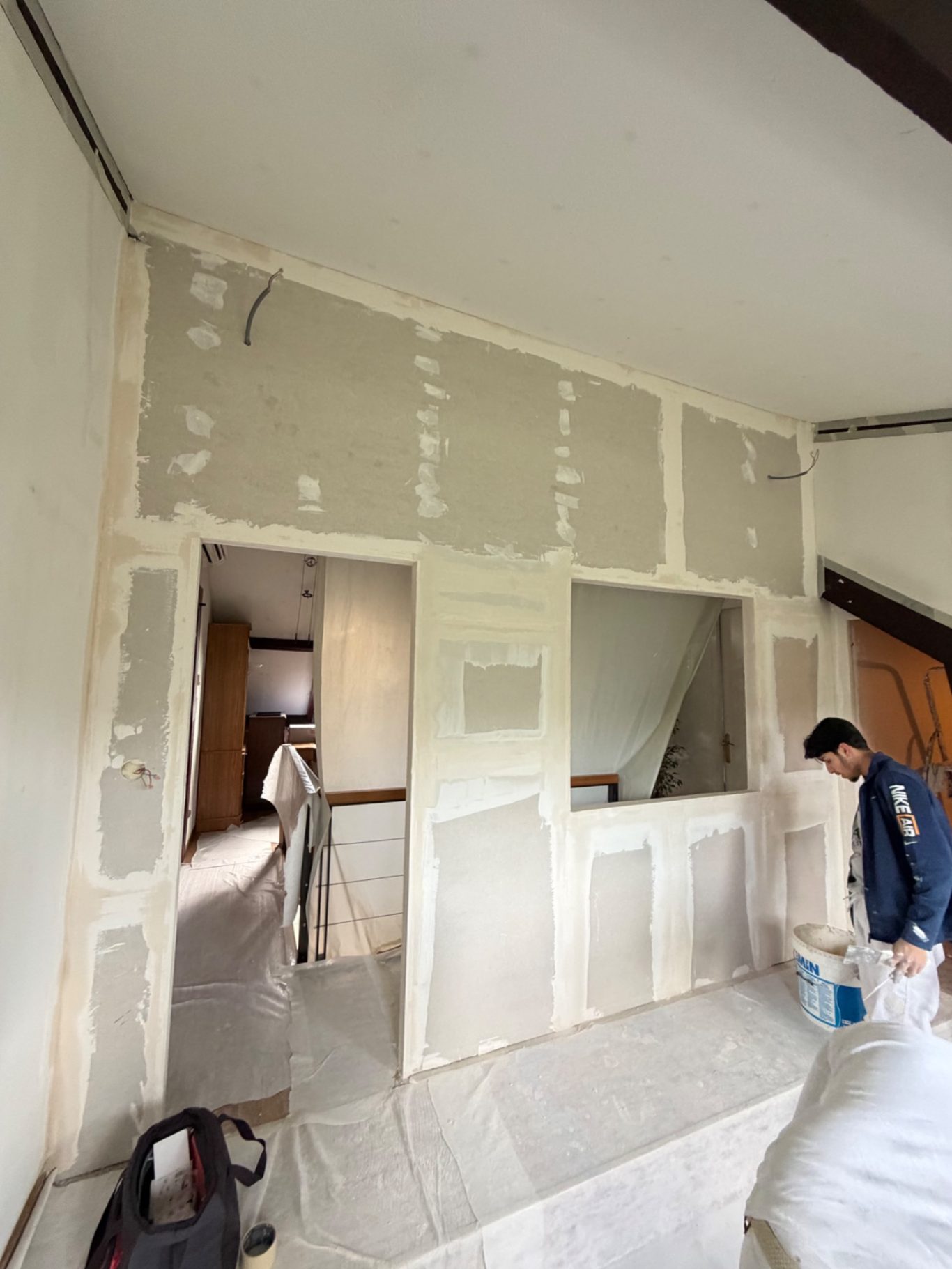 Création d'une chambre et dressing - 77 Montévrain (seine et marne) Mur en cours de finition avec plaques de plâtre et personne en train de travailler.
