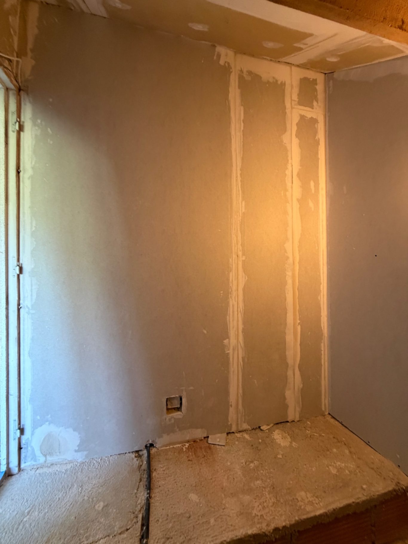 Création d'une chambre et dressing - 77 Montévrain (seine et marne) Mur de pièce avec des traces de plâtre et un éclairage doux. Sol en cours de finition.
