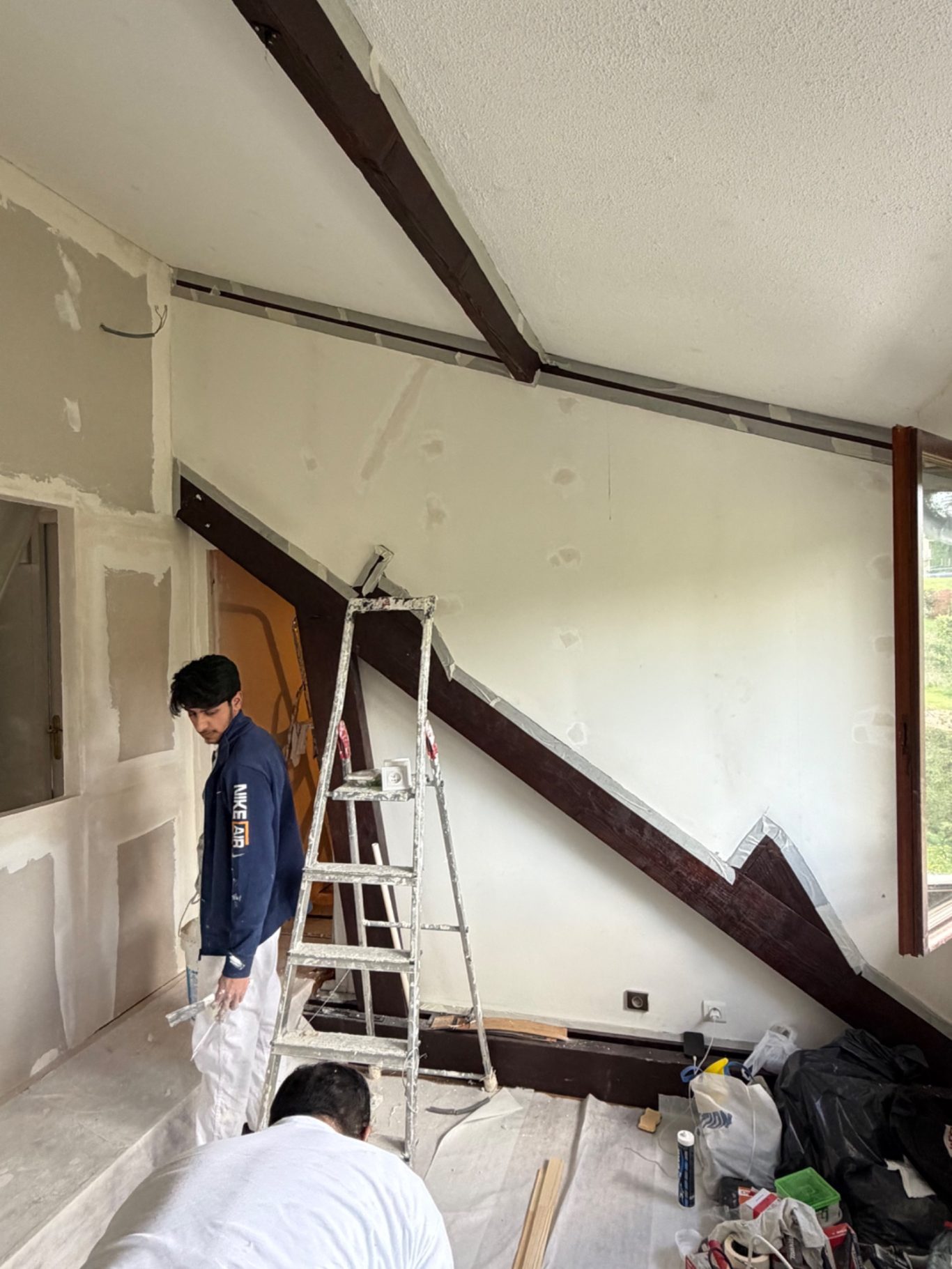 Création d'une chambre et dressing - 77 Montévrain (seine et marne) Homme devant un mur en cours de rénovation avec une échelle et des poutres apparentes.